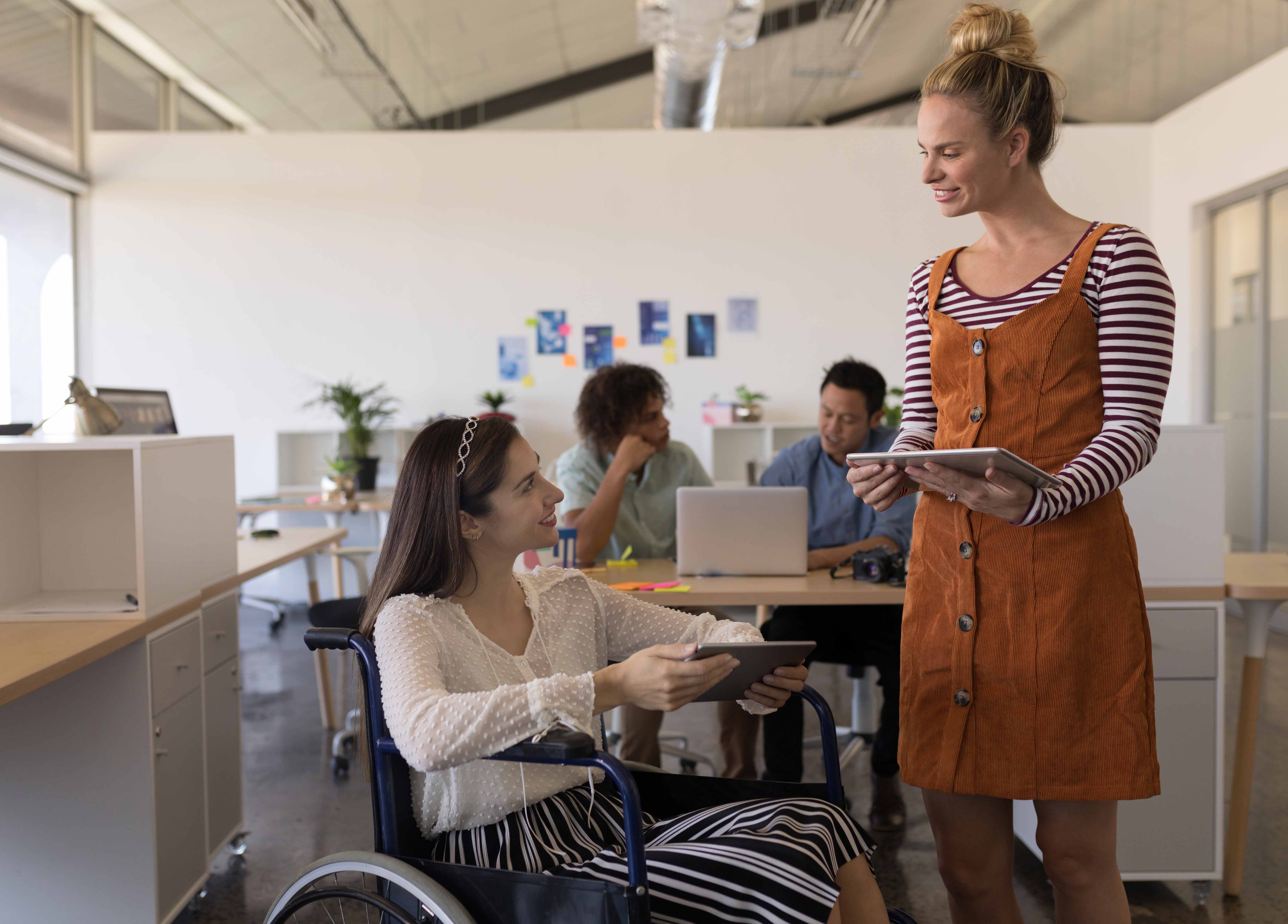 Woman with disabilities interacting with her casually dressed coworker in office