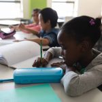 disabled schoolgirl studying and sitting at desk in classroom of elementary school