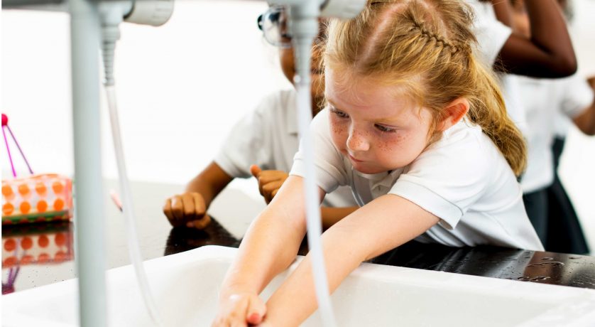 Young girl washing hands with water