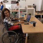 Side view of young disabled female using laptop at desk