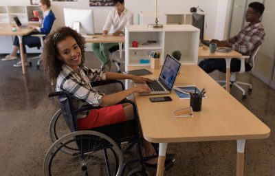 Side view of young disabled female using laptop at desk
