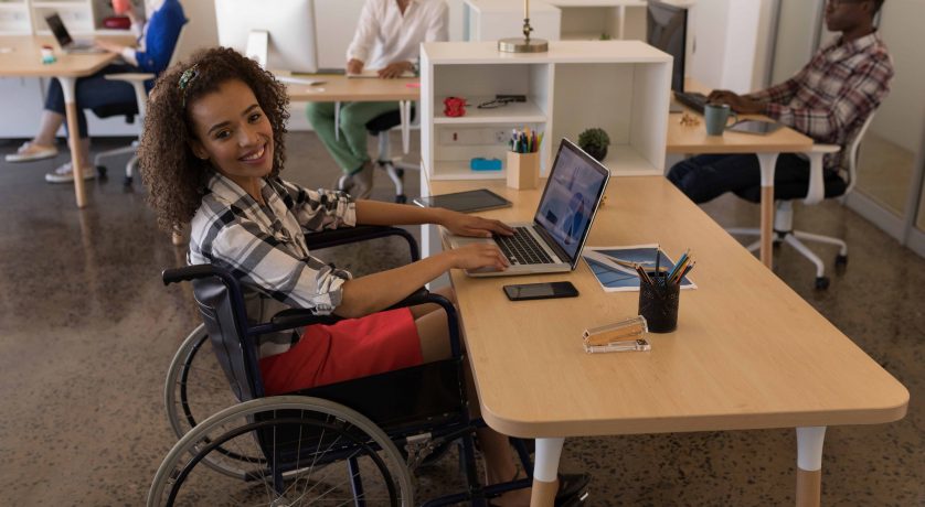 Side view of young disabled female using laptop at desk