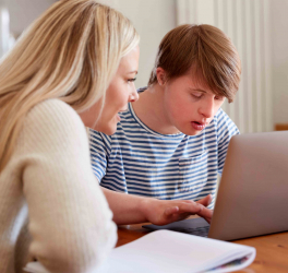Downs Syndrome Man Sitting With Tutor Using Laptop