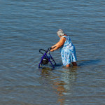 Elderly lady walks with walker in the sea