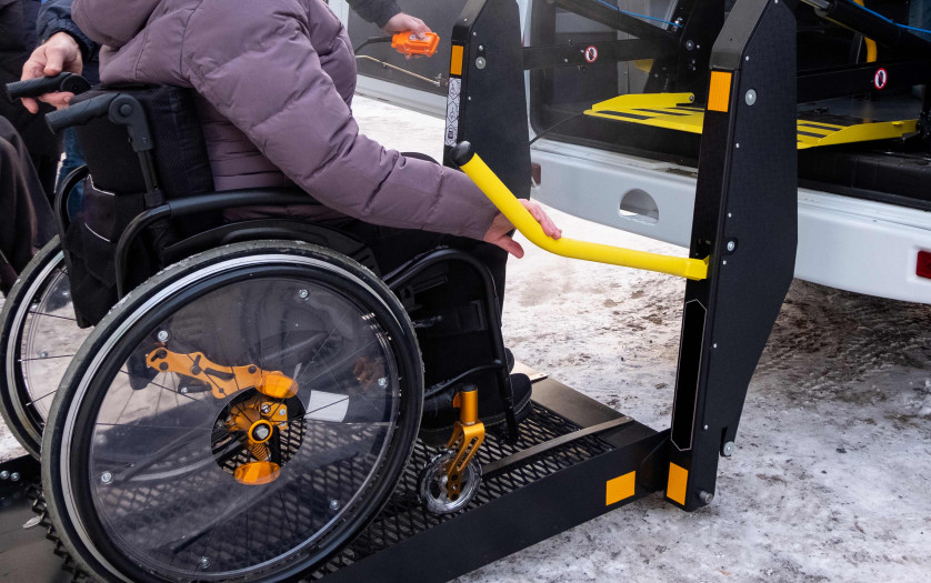 A man presses a button on the control panel to pick up a woman in a wheelchair in a taxi