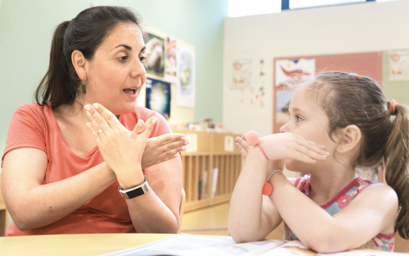 Sign language teacher in a extra tutoring class with a deaf child girl using American Sign Language