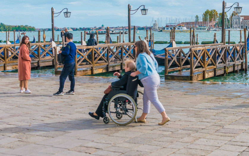 woman pushing a old woman in wheelchair at tourist site