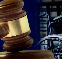 Wooden gavel with wheelchair in background
