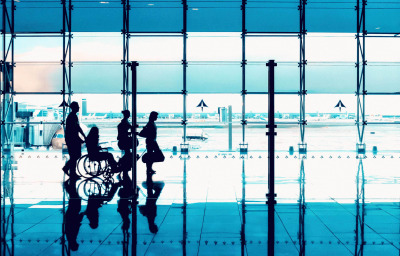 Silhouettes of people with luggage walking at airport.