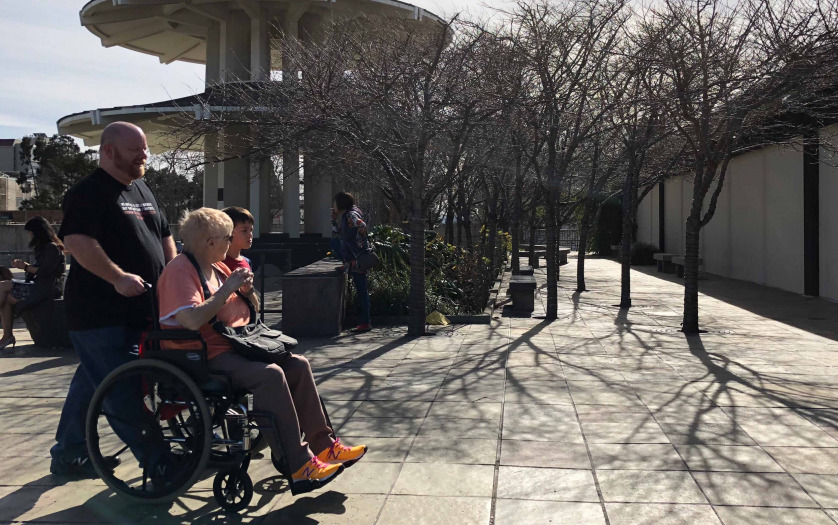 man pushing woman in wheelchair
