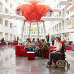 Student in wheelchair and colleagues in university lobby