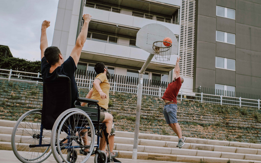 A man in wheelchair plays basketball with friends