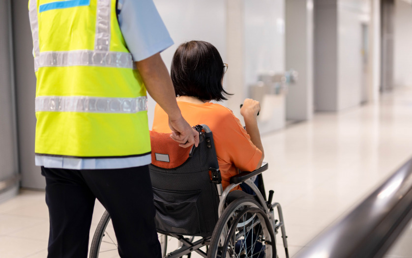 a gate attendant helps a passenger in wheelchair.