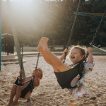 Children laughing on the swings at sunset