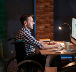 man in wheelchair working in office