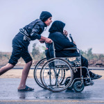 son pushing mother in wheelchair