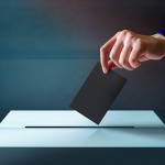 hand dropping ballot card into vote box