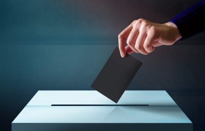 hand dropping ballot card into vote box