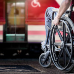 man in his wheelchair at railway station platform waiting for train