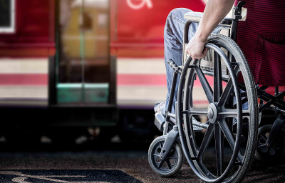 man in his wheelchair at railway station platform waiting for train