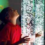 Child interacting with colored lights bubble tube lamp