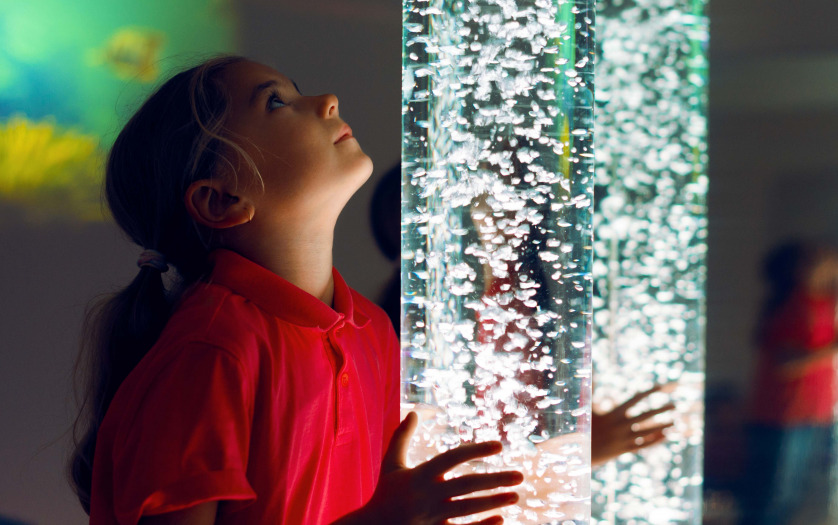 Child interacting with colored lights bubble tube lamp