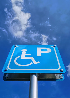 Low angle view of blue handicapped parking sign against blue cloudy sky at day time