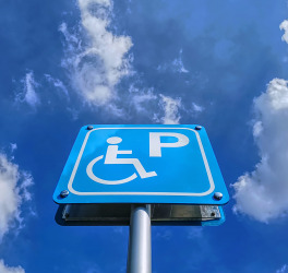 Low angle view of blue handicapped parking sign against blue cloudy sky at day time