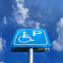 Low angle view of blue handicapped parking sign against blue cloudy sky at day time