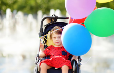 Cute little girl with cerebral palsy in a wheelchair celebrate birthday
