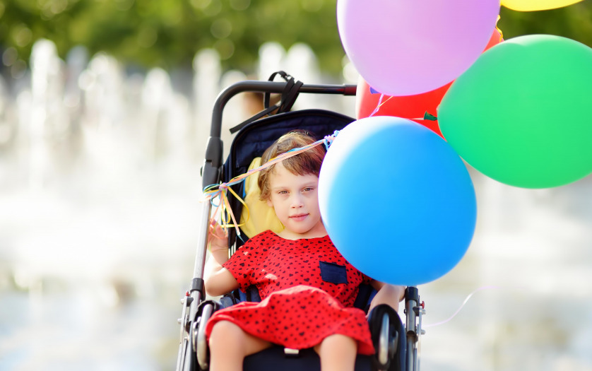Cute little girl with cerebral palsy in a wheelchair celebrate birthday