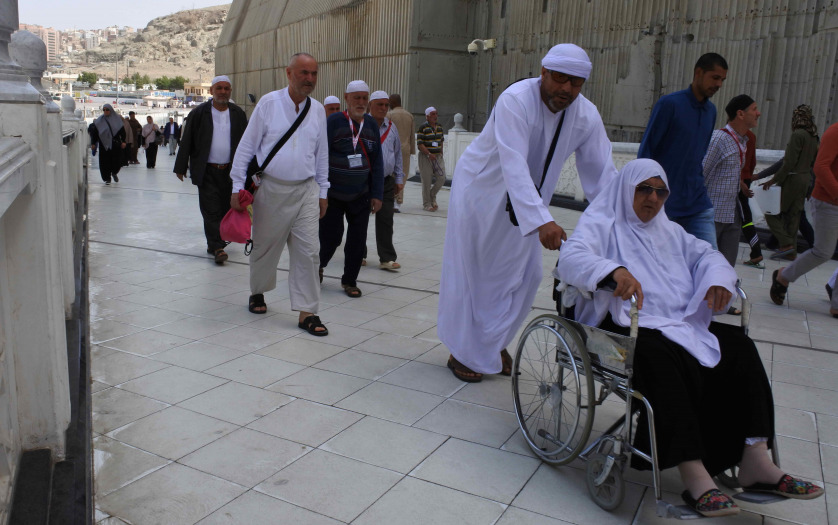 Muslim pilgrims put on their white ihrams praying in the holy Kaaba during Hajj in Saudi Arabia with wheelchair