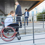 Woman in a wheelchair on a ramp in front of the office