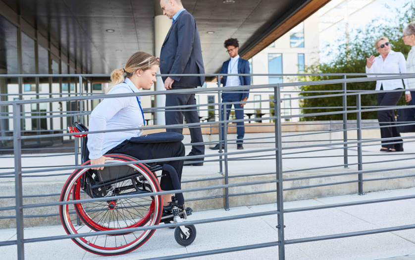 Woman in a wheelchair on a ramp in front of the office