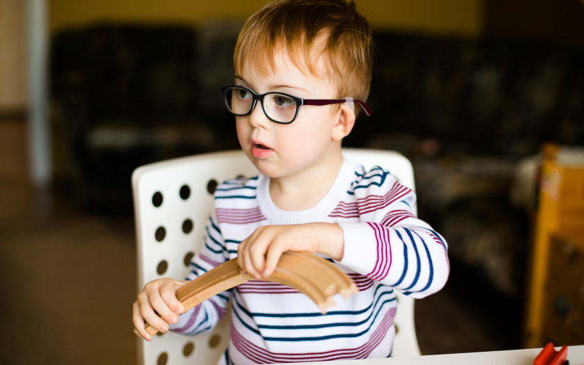Little boy with disability in the glasses playing