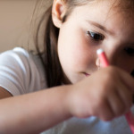 Attentive 5 years old child girl painting with felt-tip pen.