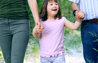 Beautiful little girl with down syndrome walking with parents