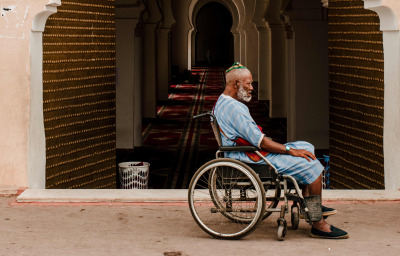 Muslim man in wheelchair at the door of the mosque.