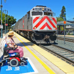 A disabled woman ready for boarding watches her Caltrain passenger train arrive.
