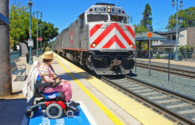 A disabled woman ready for boarding watches her Caltrain passenger train arrive.