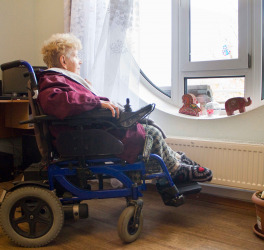 A woman in wheelchair looks out the window.