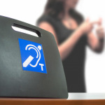 Two deaf people using American Sign Language next to a Tele Coil Magnetic Loop with T-switch with induction system for hearing aids