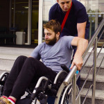 A man helping to move down the stairs to a disabled person in a wheelchair