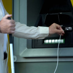 Blind man searching audio jack in talking atm, using headset to withdraw money.