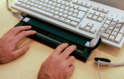 Blind person using computer with braille computer display