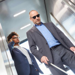 Blind men with glasses and cane in elevator in business office