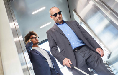 Blind men with glasses and cane in elevator in business office