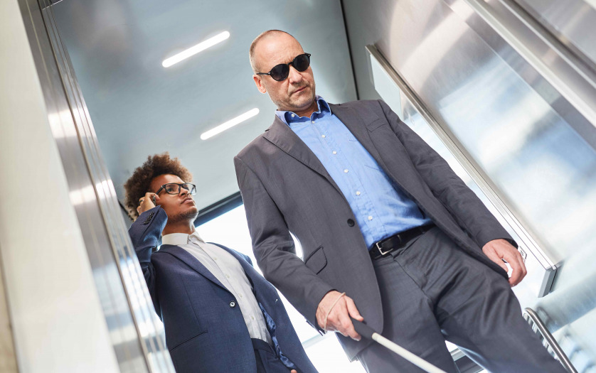 Blind men with glasses and cane in elevator in business office