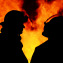 A striking silhouette image of two firemen called to an Australian bushfire blaze that started at night time. The men are discussing their plans for controlling the blazing flames.