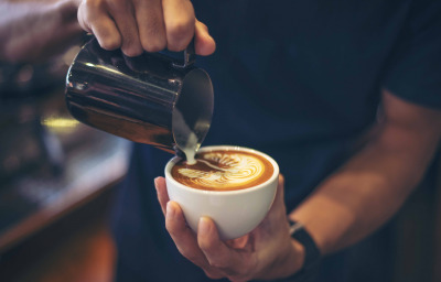Close-up of hands barista make latte coffee art paint